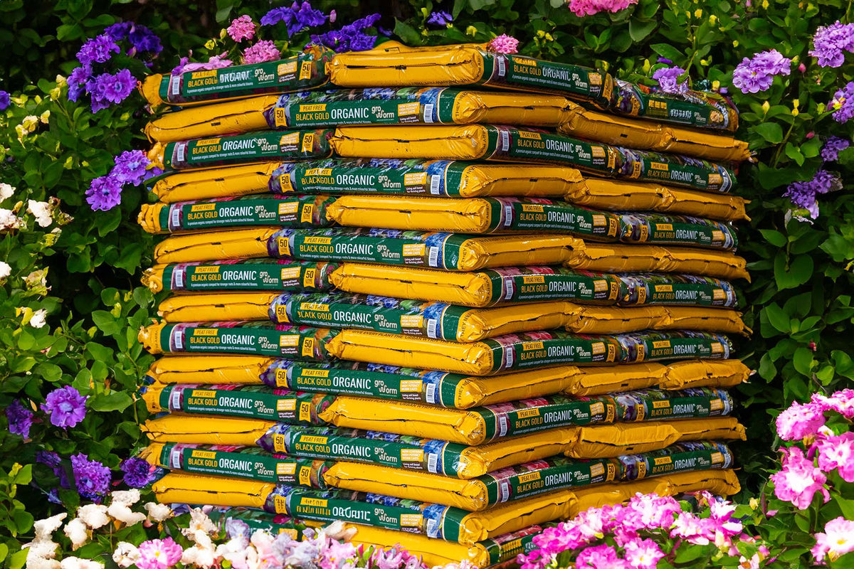 A stacked display of Growmoor compost bags surrounded by colourful flowers