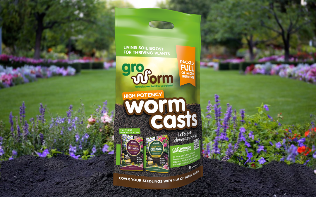 A green Gro Worm Worm Casts pouch standing in a flower garden